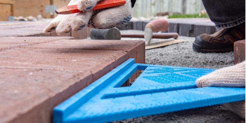 installing-paver-bricks-for-patio-in-backyard-a-workmans-gloved-hands-picture-id1170203949